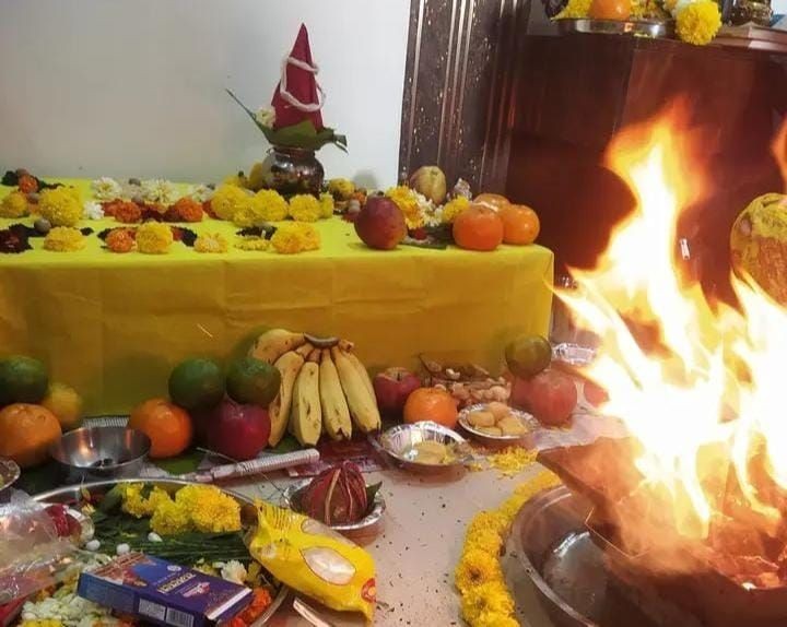 Traditional Indian puja setup with offerings, flowers, and a sacred fire ceremony.