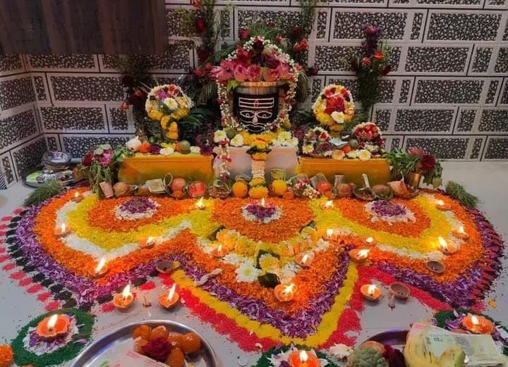 Colorful floral Rangoli and decorated altar with lights and offerings for a Hindu festival celebration.