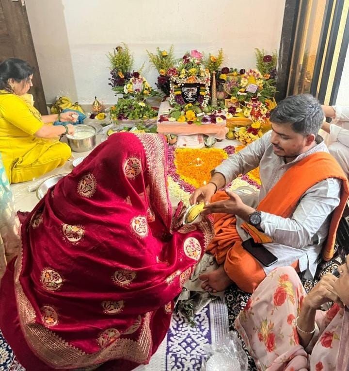 People participating in a traditional Indian ceremony with colorful decorations and offerings.