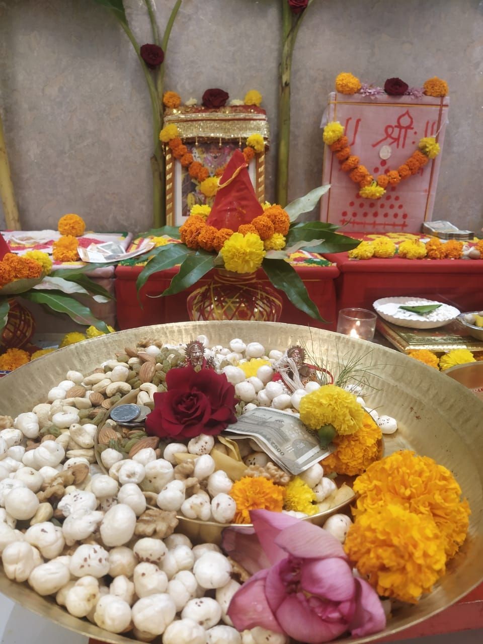 Decorated religious altar with flowers, snacks, and offerings in a traditional Indian setting.